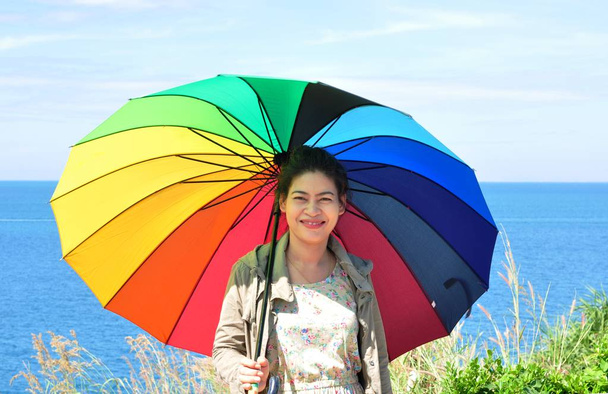 aziatische vrouw met paraplu op zee kust - Foto, afbeelding