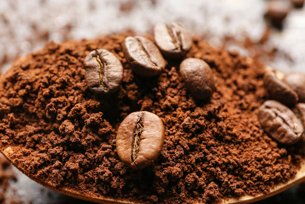Spoon with coffee beans and powder, closeup - Fotó, kép