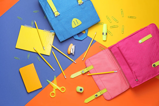 School backpacks and stationery on color background - Foto, afbeelding
