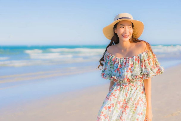 Portret mooie jonge aziatische vrouw gelukkig glimlach ontspannen rond tropische strand zee oceaan op blauwe hemel voor ontspanning - Foto, afbeelding