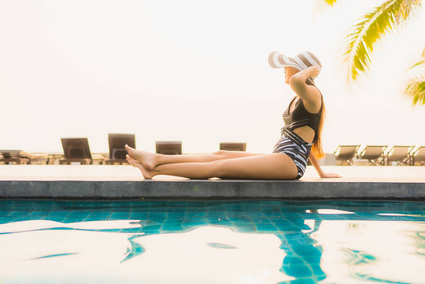 Портрет красивая молодая азиатская женщина расслабиться вокруг открытый бассейн в отеле курорта с пальмой на закате или восходе солнца для отдыха - Фото, изображение