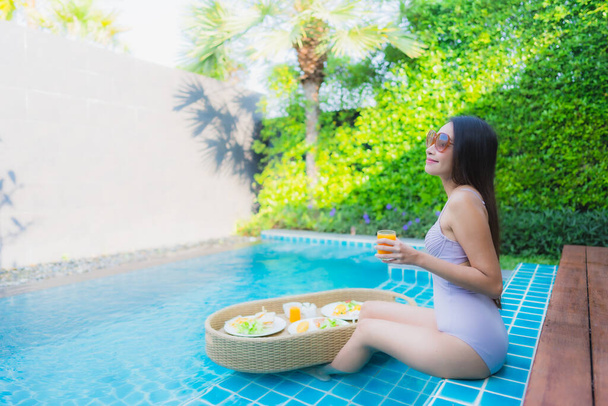 Portret młoda azjatycka kobieta szczęśliwy uśmiech cieszyć się pływające śniadanie taca w basenie w ośrodku hotelowym - Zdjęcie, obraz