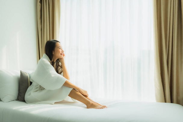 młody Azji kobieta szczęśliwy uśmiech relaks na łóżko w sypialni wnętrze - Zdjęcie, obraz