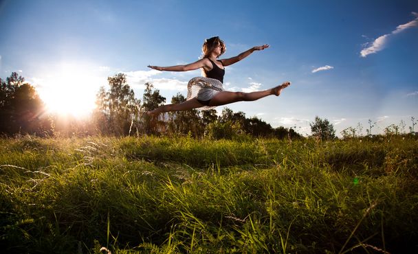 Девушка делает разрыв во время прыжка на поле
 - Фото, изображение