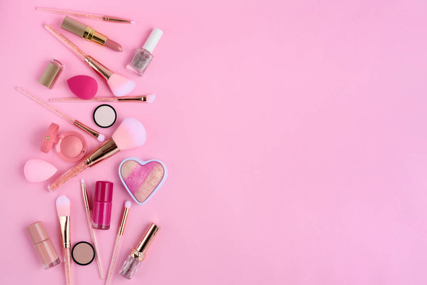 Makeup brushes and decorative cosmetics on pink background, with empty space for text. Top view - 写真・画像