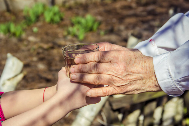 Grandmother giving a glass of clean water to a child. Selective focus. - Photo, Image
