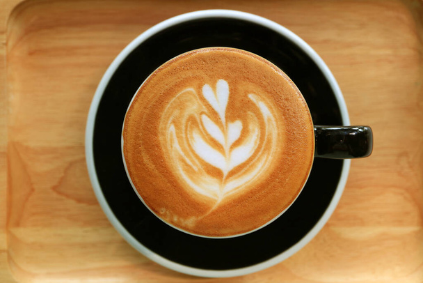 Bovenaanzicht van een kopje cappuccino koffie met mooie latte art - Foto, afbeelding