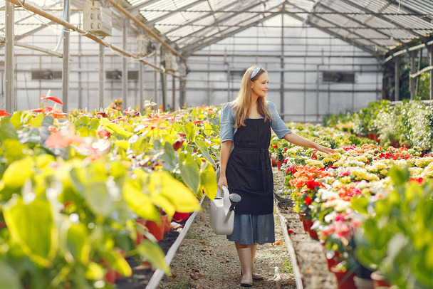 Woman in a black apron working in a greenhouse - Foto, Imagen