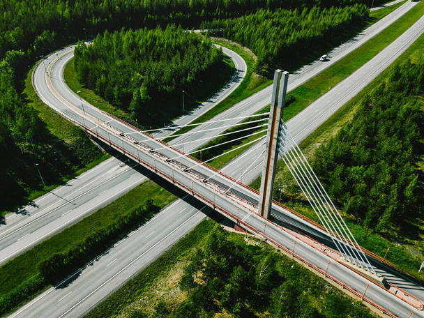 Aerial top view of cable-stayed Suspension bridge and Highway road with green forests on a summer day in Finland. - Photo, Image