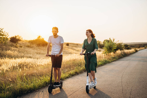 Young couple on vacation having fun driving electric scooter on the road in the countryside. Content technologies. Copy space. - Fotografie, Obrázek