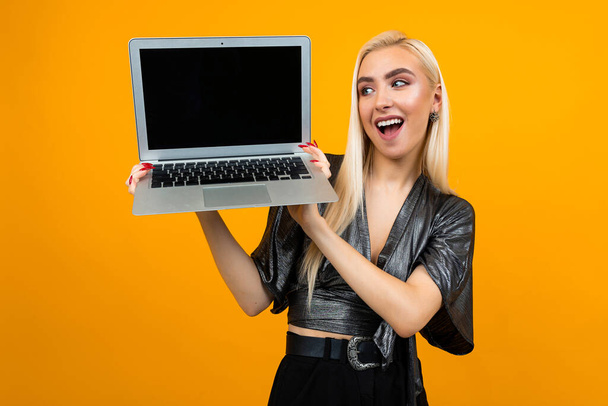 european girl holding laptop with blank screen for web page on yellow background - Photo, Image