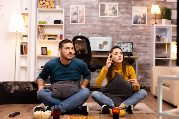 Coppia seduta sul pavimento e guardare la TV nel loro soggiorno
 - Foto, immagini