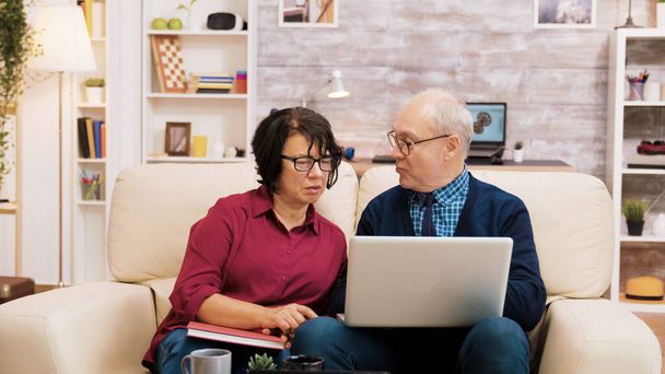 Starší pár sedí na pohovce pomocí notebooku pro online nakupování - Fotografie, Obrázek