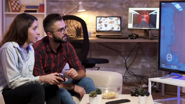 Homme assis sur le canapé apprenant à sa petite amie à jouer à des jeux vidéo
 - Photo, image