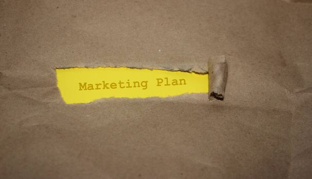 ブラウン包装紙は、単語マーケティング計画を明らかにするために引き裂かれた。事業概念 . - 写真・画像