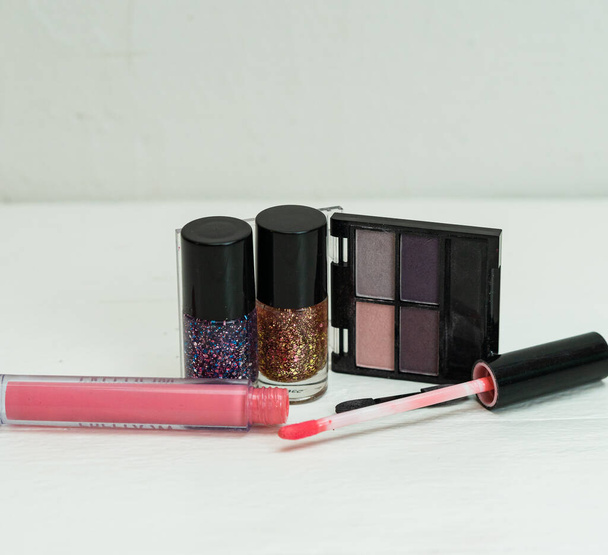 Vloeibare lippenstift met applicator, oogschaduw palet en kleurrijke nagellak geïsoleerd op wit met kopieerruimte. - Foto, afbeelding