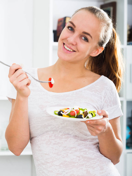 portrait of happy young woman with chestnut hair eating salad at kitchen - Foto, immagini