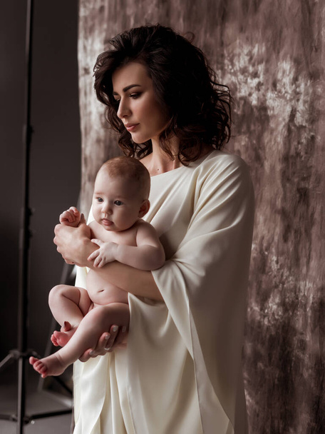 Pretty woman holding a newborn baby in her arms. A mother's love. A woman holds in her arms her baby girl. 4 month baby - Photo, Image