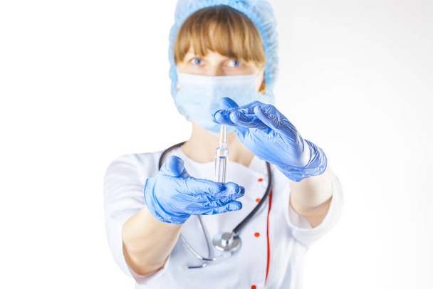 Médica feminina em um casaco branco e máscara com um medicamento experimental em suas mãos. Estúdio foto - Foto, Imagem