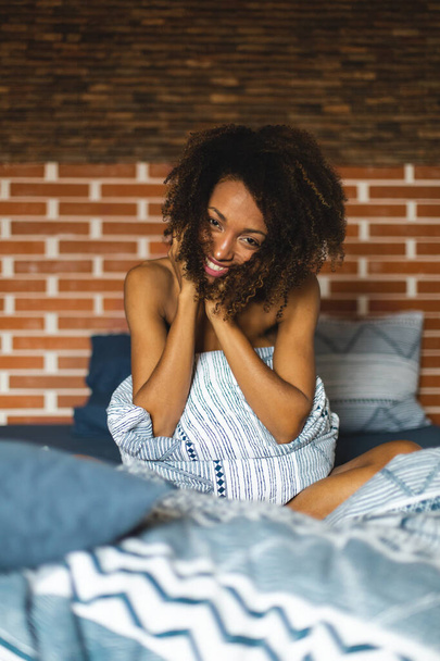 Natural charming young black woman in bed portrait. Afro hairstyle female waking up in the morning. - Фото, зображення