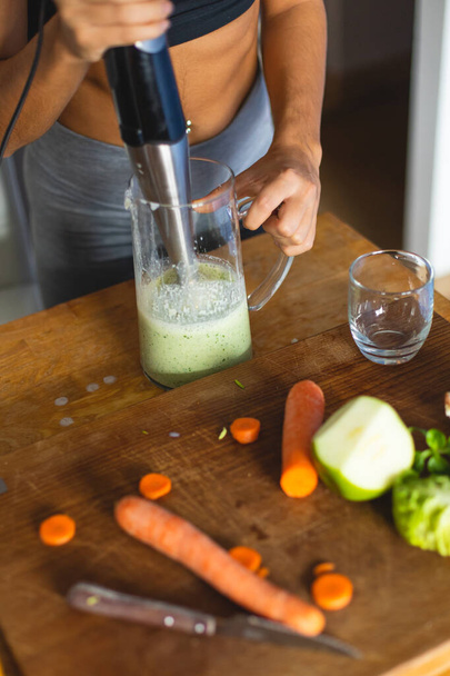 Detail einer Frau in der Küche, die mit einem Mixer einen grünen, gesunden Detox-Smoothie zubereitet. - Foto, Bild