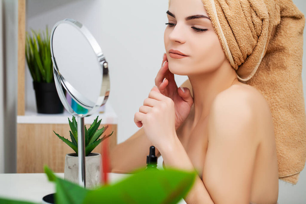 Woman getting ready for work doing morning makeup in bathroom mirror at home - Photo, Image
