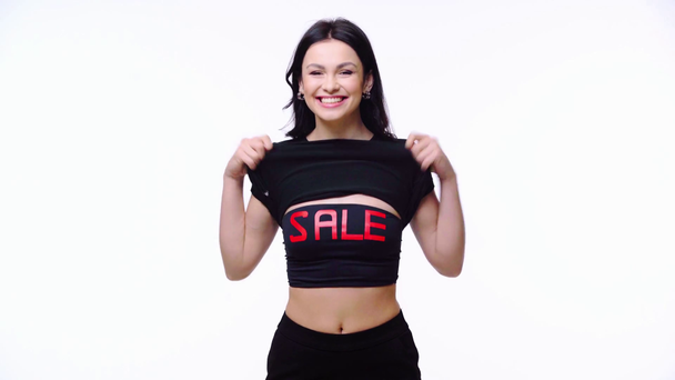 Mujer excitada mostrando top con venta de letras aisladas en blanco - Imágenes, Vídeo