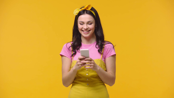 Woman chatting on smartphone isolated on yellow - Video, Çekim