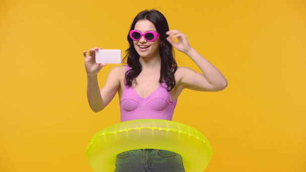 Mulher feliz com anel inflável tomando selfie isolado no amarelo
 - Filmagem, Vídeo