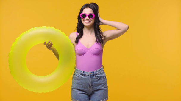 Vrouw zwaaiende hand en houden opblaasbare ring geïsoleerd op geel - Video