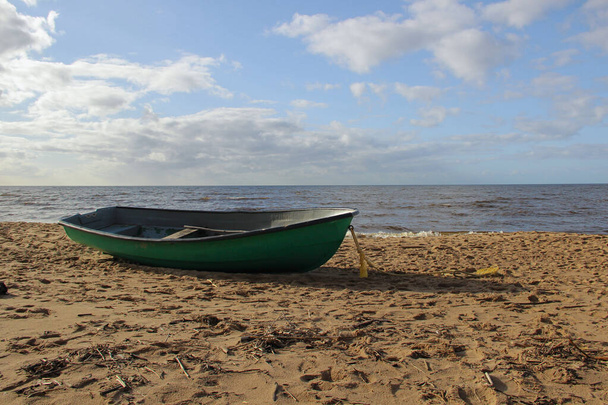 Vissersboot die aan het strand lag. Baltische strand en het landschap in een zonnige dag. Oostzee zeelieden vervoer is een vissersboot.  - Foto, afbeelding