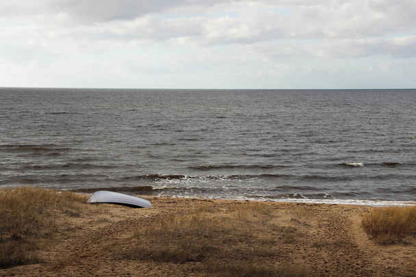 Rybářský člun, který ležel na pláži. Baltská pláž a její krajina v zamračeném dni. Baltští námořníci jsou rybářská loď. Dramatické panorama pláže,  - Fotografie, Obrázek