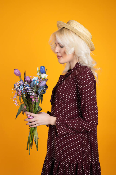 Attractive blonde girl posing with flowers isolated on yellow background - Fotografie, Obrázek