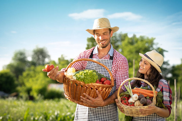 Couple farmers with baskets full of fresh vegetables from farm.  Just look at how bright and fresh these are - Foto, Bild