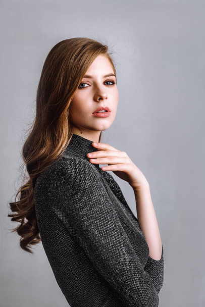 Model girl with beautiful hands on a gray background. Portrait of a beautiful brunette. - Fotografie, Obrázek