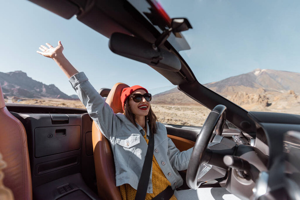 Vrouw reist per cabriolet auto op de woestijnweg - Foto, afbeelding