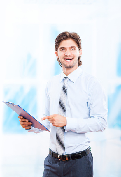 Business man with clipboard in bright blue office - Foto, immagini