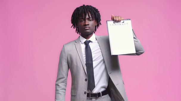 アフリカ系アメリカ人のビジネスマンがピンクに隔離された契約書を書いて見せる - 映像、動画