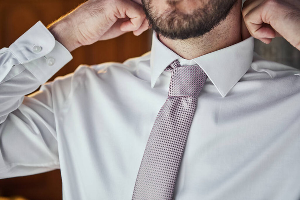 man in shirt dressing up and adjusting tie on neck at home. Men Fashion - Photo, Image
