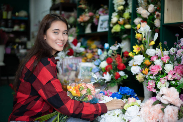 Femme souriante fleuriste propriétaire d'un magasin de fleurs de petite entreprise et jeune fleuriste examinant les fleurs à la boutique
 - Photo, image