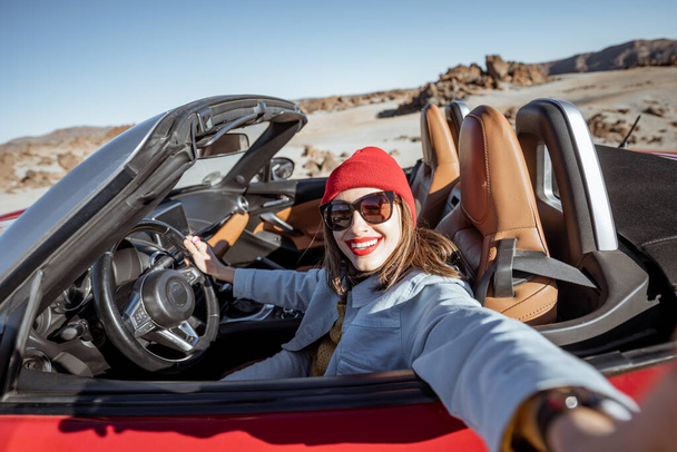 Женщина, путешествующая на кабриолете по пустынному велли
 - Фото, изображение