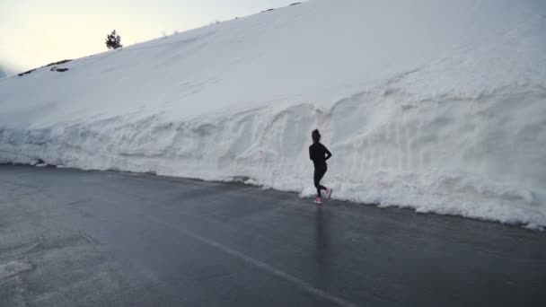 Selbstbewusste Frau in Jogginghose läuft in Schneekorridor in den Bergen Bulgariens - Filmmaterial, Video