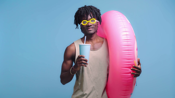Homem americano africano com anel inflável e copo descartável isolado em azul
 - Filmagem, Vídeo