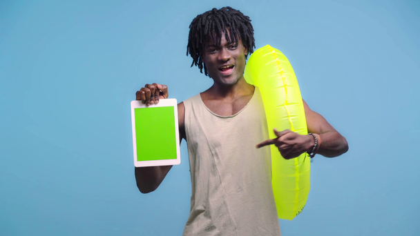 Африканський американець з кільцем для плавання показує цифрову табличку і як знак ізольований на синьому - Кадри, відео