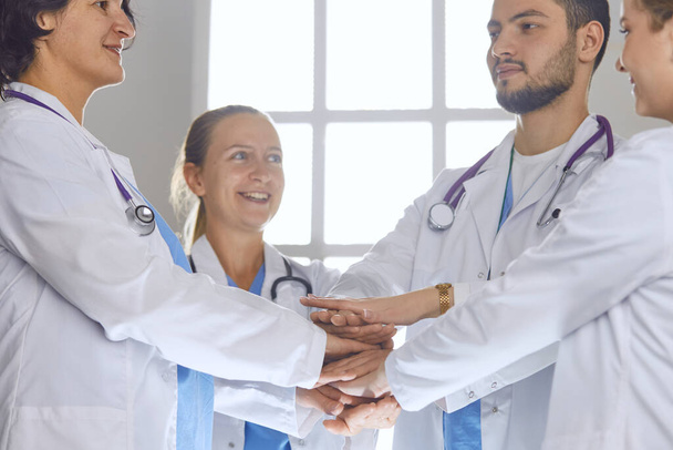 Team of medical workers holding hands together indoors, above view. Unity concept - Photo, Image