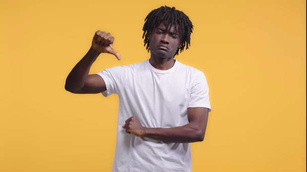 Africano americano homem com polegar para baixo isolado no amarelo
 - Filmagem, Vídeo