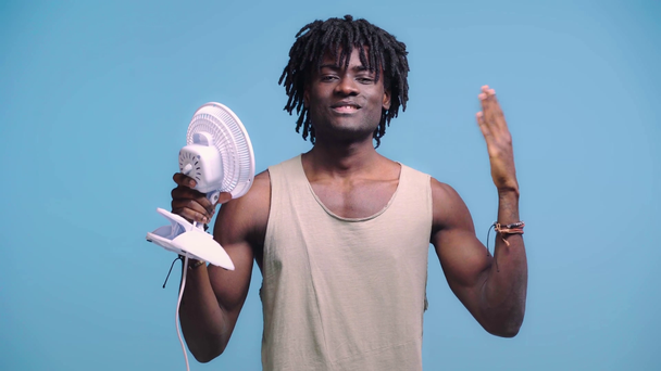 Africano americano com ventilador isolado em azul
 - Filmagem, Vídeo