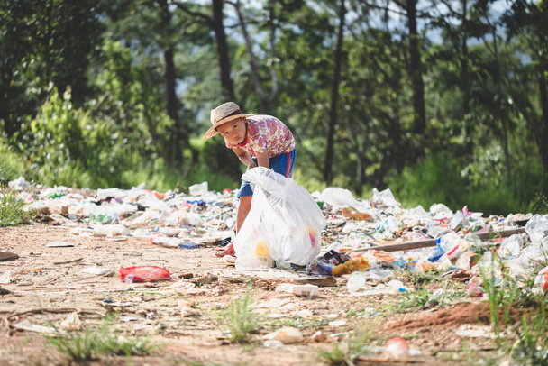 Un chico pobre recogiendo residuos de basura de un vertedero en las afueras, las vidas y estilos de vida de los pobres, Trabajo infantil, Pobreza y Medio Ambiente Conceptos - Foto, imagen