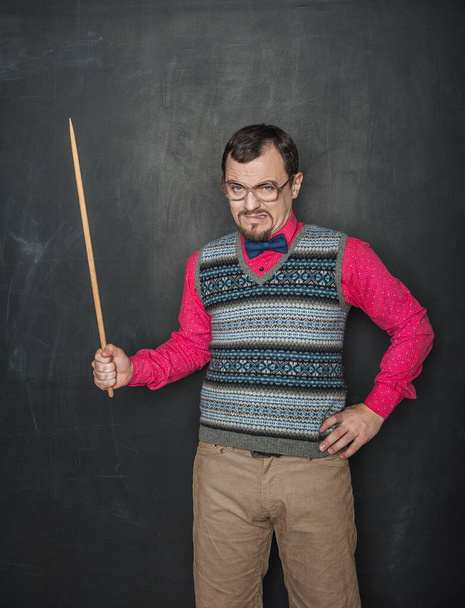 Angry teacher in retro style with pointer on blackboard background - Foto, afbeelding