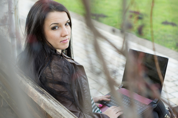 Молодая красивая брюнетка студентка в профиль сидит на скамейке около
 - Фото, изображение